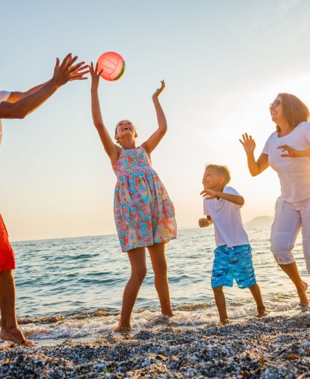 Rodzina grająca w siatkówkę na plaży w Sarbinowie – wakacje w domkach letniskowych